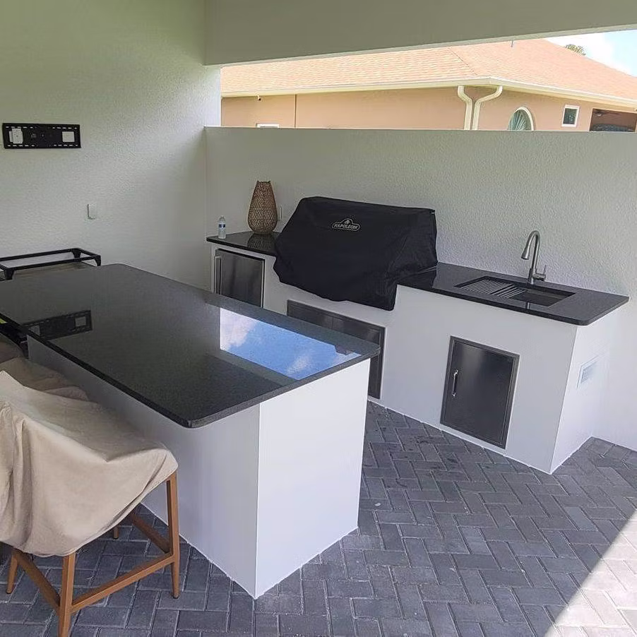 Custom outdoor kitchen with grill, stone counters, and pergola